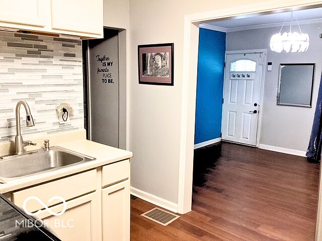 2419 Mars Hill St, Indianapolis, IN 46241 - kitchen featuring dark wood-type flooring, decorative backsplash, light countertops, crown molding, and a chandelier