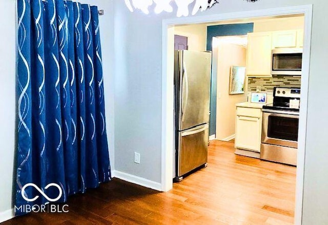 2419 Mars Hill St, Indianapolis, IN 46241 - kitchen featuring stainless steel appliances, light wood-style flooring, decorative backsplash, and white cabinets