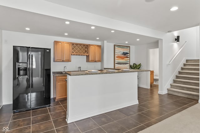9877 Wading Crane Ave, Fishers, IN 46055 - kitchen with fridge with ice dispenser, recessed lighting, dark tile patterned floors, dark stone counters, and a kitchen island
