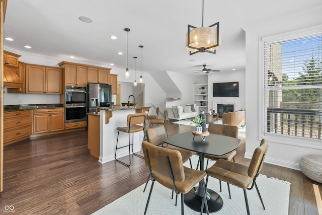 9877 Wading Crane Ave, Fishers, IN 46055 - dining space with recessed lighting, dark wood-style flooring, a glass covered fireplace, ceiling fan, and built in shelves