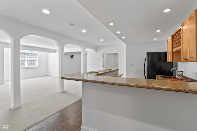 9877 Wading Crane Ave, Fishers, IN 46055 - kitchen with freestanding refrigerator, arched walkways, recessed lighting, dark tile patterned flooring, and dark colored carpet