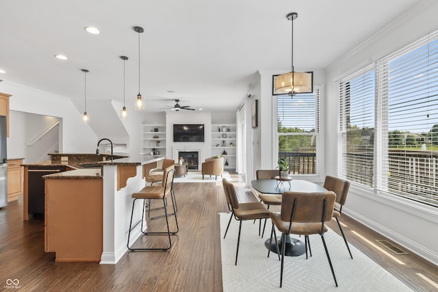 9877 Wading Crane Ave, Fishers, IN 46055 - dining area with a ceiling fan, dark wood-style flooring, a glass covered fireplace, crown molding, and built in features