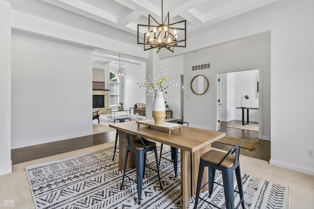 9877 Wading Crane Ave, Fishers, IN 46055 - dining space with a chandelier, a glass covered fireplace, beam ceiling, coffered ceiling, and a high ceiling