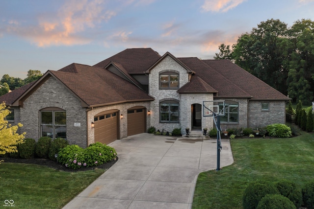9877 Wading Crane Ave, Fishers, IN 46055 - french country inspired facade featuring a garage, driveway, a front yard, brick siding, and roof with shingles