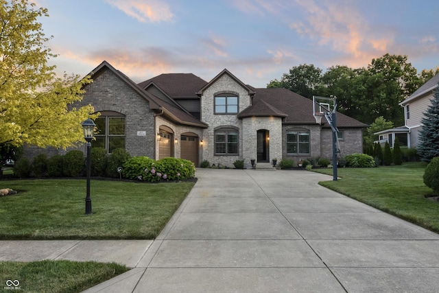 9877 Wading Crane Ave, Fishers, IN 46055 - french provincial home featuring driveway, a front yard, stone siding, a shingled roof, and an attached garage