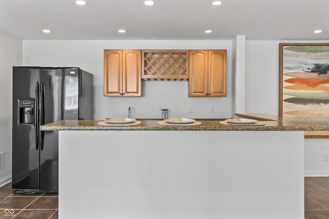 9877 Wading Crane Ave, Fishers, IN 46055 - kitchen with black refrigerator with ice dispenser, dark tile patterned flooring, dark stone counters, recessed lighting, and a kitchen island