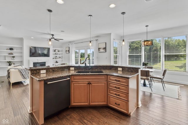 9877 Wading Crane Ave, Fishers, IN 46055 - kitchen featuring dishwasher, a glass covered fireplace, a ceiling fan, dark wood-type flooring, and a kitchen island with sink