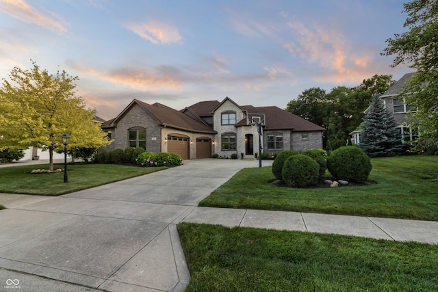 9877 Wading Crane Ave, Fishers, IN 46055 - french country home featuring an attached garage, concrete driveway, a yard, and stone siding