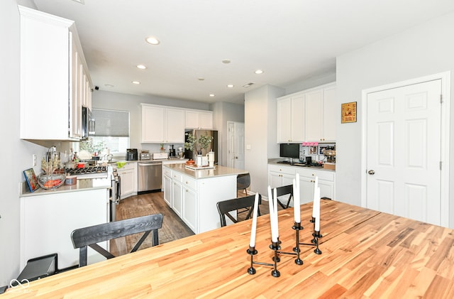 4309 Maize Ln, Whitestown, IN 46075 - kitchen featuring appliances with stainless steel finishes, wood finished floors, recessed lighting, white cabinets, and a kitchen island