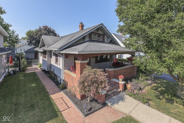 1005 Main St, Beech Grove, IN 46107 - view of front of house featuring a front yard, roof with shingles, a porch, and a chimney