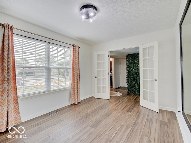 3902 Jekyll Ct, Indianapolis, IN 46237 - spare room featuring french doors, light wood-type flooring, and a textured ceiling
