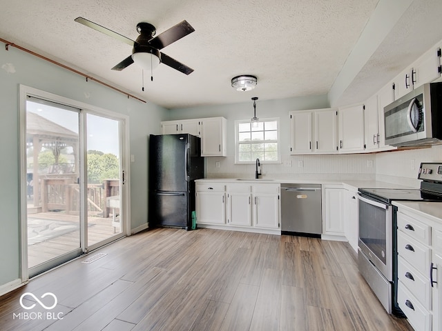 3902 Jekyll Ct, Indianapolis, IN 46237 - kitchen with stainless steel appliances, a textured ceiling, light countertops, light wood-type flooring, and white cabinets