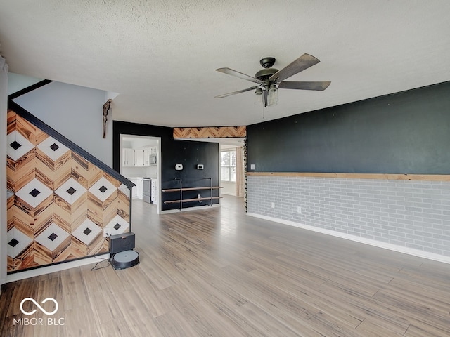 3902 Jekyll Ct, Indianapolis, IN 46237 - unfurnished living room featuring a ceiling fan, wood finished floors, a textured ceiling, and brick wall