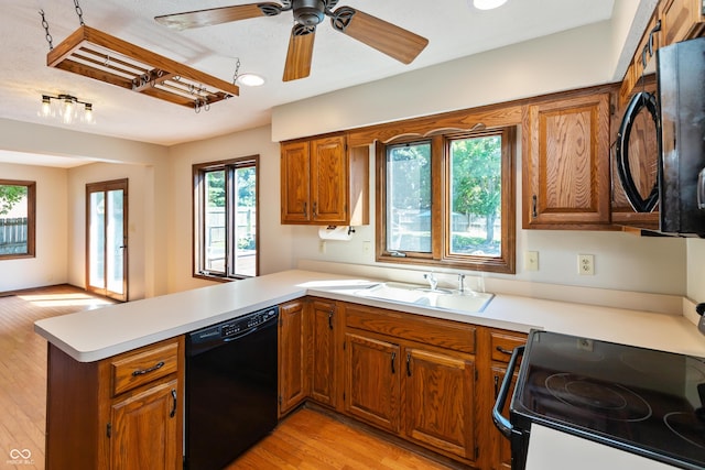 6926 Princess Ln, Avon, IN 46123 - kitchen featuring black appliances, a peninsula, brown cabinets, light countertops, and light wood finished floors