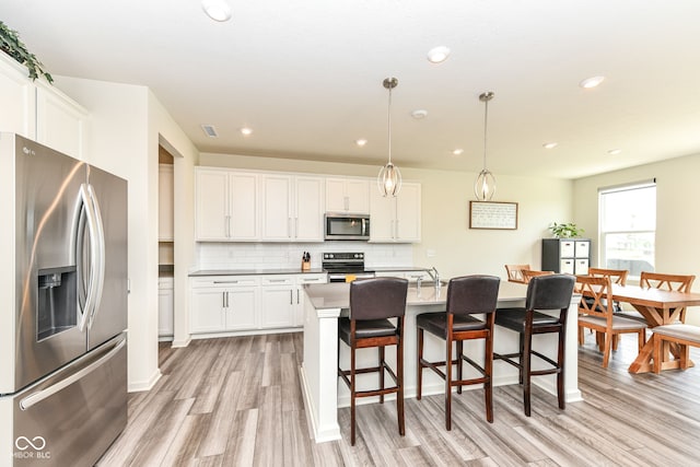 7101 Oak Trace Ln, Brownsburg, IN 46112 - kitchen with stainless steel appliances, light wood finished floors, backsplash, a kitchen bar, and white cabinetry