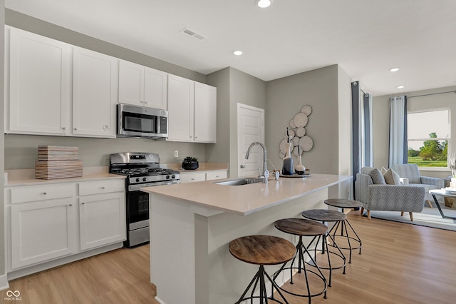 918 Shadow Dr, Danville, IN 46122 - kitchen with stainless steel appliances, light wood finished floors, a kitchen breakfast bar, white cabinetry, and recessed lighting