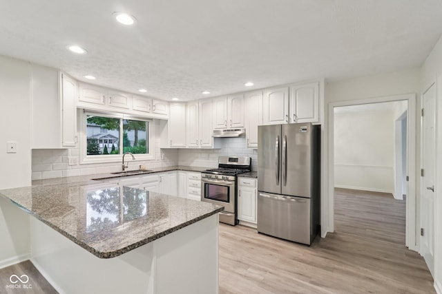 11845 Discovery Cir, Indianapolis, IN 46236 - kitchen featuring stainless steel appliances, a peninsula, under cabinet range hood, dark stone counters, and white cabinetry