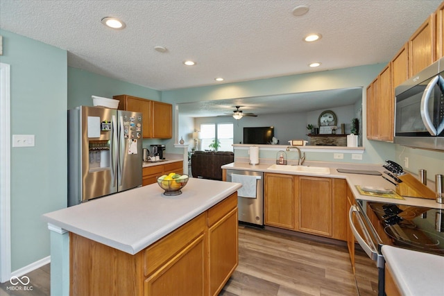 7950 Crackling Ln, Indianapolis, IN 46259 - kitchen featuring appliances with stainless steel finishes, a textured ceiling, light countertops, a ceiling fan, and light wood-style floors