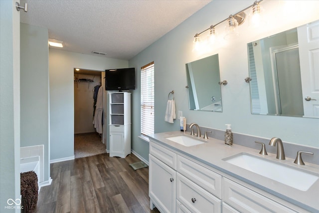 7950 Crackling Ln, Indianapolis, IN 46259 - full bath with a textured ceiling, wood finished floors, double vanity, a shower with door, and a spacious closet