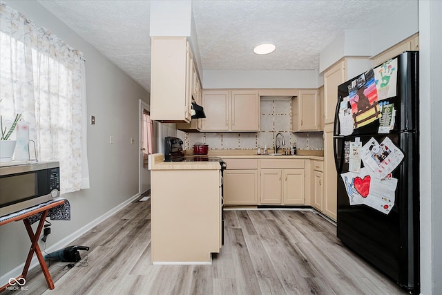 2466 Sickle Rd, Indianapolis, IN 46219 - kitchen with freestanding refrigerator, stainless steel microwave, a textured ceiling, light wood-type flooring, and light countertops
