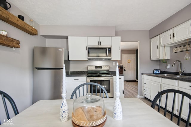 1743 Chandler Ln, Columbus, IN 47203 - kitchen with appliances with stainless steel finishes, white cabinetry, wood finished floors, open shelves, and a textured ceiling