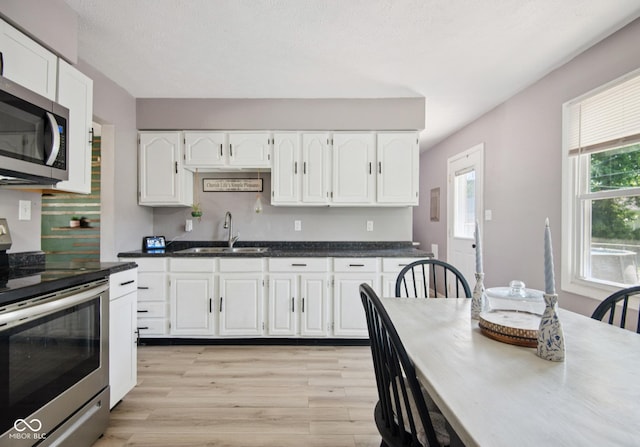 1743 Chandler Ln, Columbus, IN 47203 - kitchen with appliances with stainless steel finishes, light wood finished floors, white cabinetry, dark countertops, and backsplash