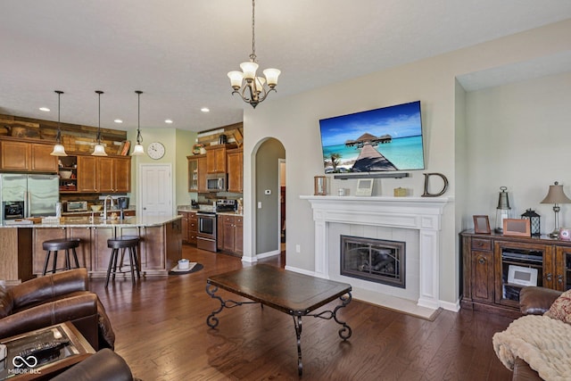 1387 Mayfield Ct, Westfield, IN 46074 - living room featuring arched walkways, dark wood-type flooring, a chandelier, recessed lighting, and a tile fireplace