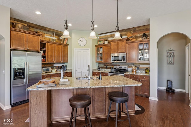 1387 Mayfield Ct, Westfield, IN 46074 - kitchen featuring stainless steel appliances, brown cabinetry, a kitchen bar, tasteful backsplash, and recessed lighting