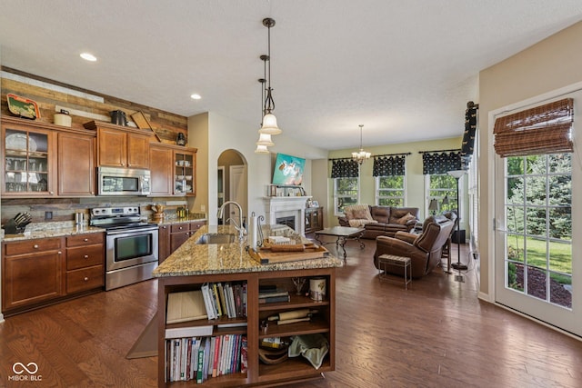 1387 Mayfield Ct, Westfield, IN 46074 - kitchen featuring appliances with stainless steel finishes, brown cabinetry, open shelves, arched walkways, and dark wood-style floors