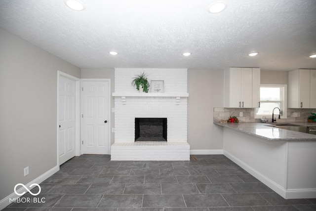 7950 N 475 E, Columbus, IN 47203 - kitchen with white cabinets, recessed lighting, a textured ceiling, a brick fireplace, and backsplash