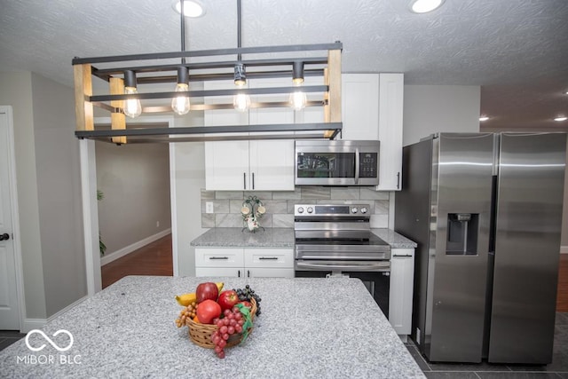 7950 N 475 E, Columbus, IN 47203 - kitchen featuring stainless steel appliances, white cabinetry, a textured ceiling, light stone counters, and backsplash