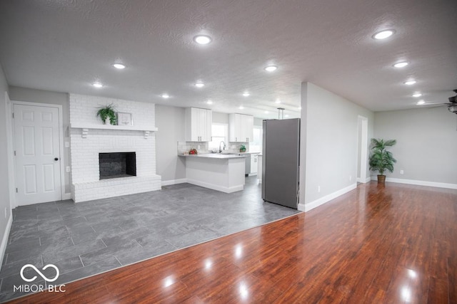 7950 N 475 E, Columbus, IN 47203 - unfurnished living room with recessed lighting, a brick fireplace, a textured ceiling, a ceiling fan, and dark wood-style flooring