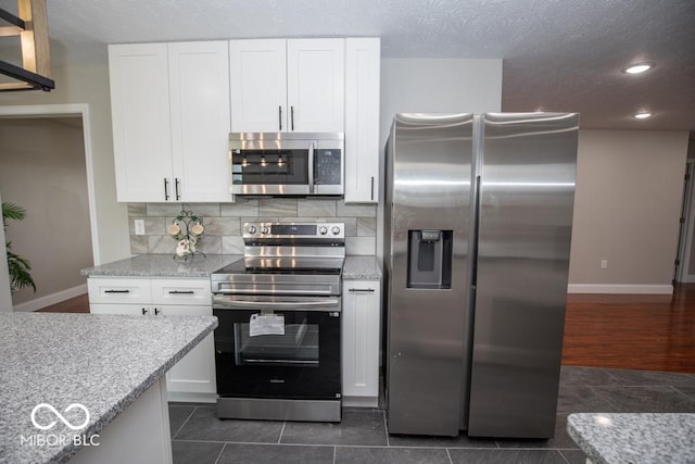 7950 N 475 E, Columbus, IN 47203 - kitchen with stainless steel appliances, white cabinets, light stone countertops, recessed lighting, and backsplash