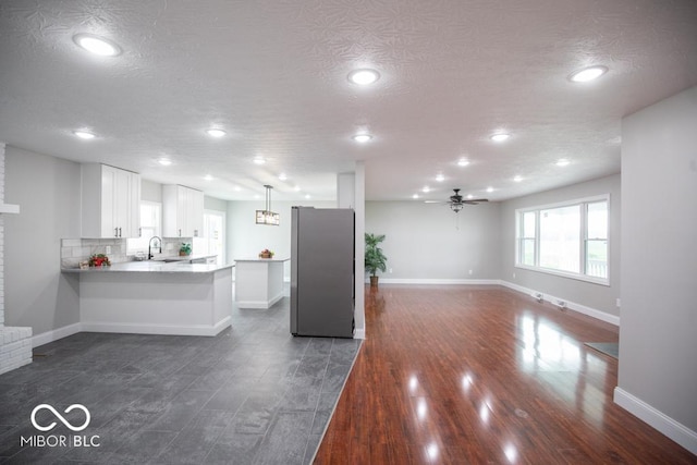 7950 N 475 E, Columbus, IN 47203 - kitchen with freestanding refrigerator, a ceiling fan, open floor plan, white cabinetry, and a peninsula