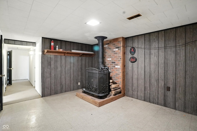 5560 Royal Oak Ct, Indianapolis, IN 46227 - finished basement featuring a wood stove, wood walls, and tile patterned floors