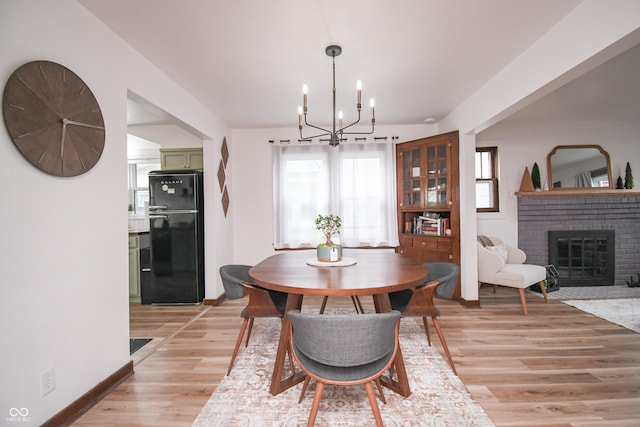 1606 California St, Columbus, IN 47201 - dining room with a chandelier, light wood finished floors, and a brick fireplace