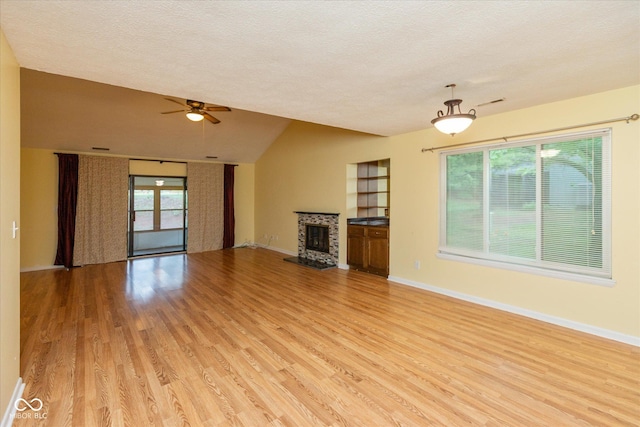 5038 Hawthorne Way, Avon, IN 46123 - unfurnished living room with light wood-type flooring, ceiling fan, a textured ceiling, vaulted ceiling, and a glass covered fireplace