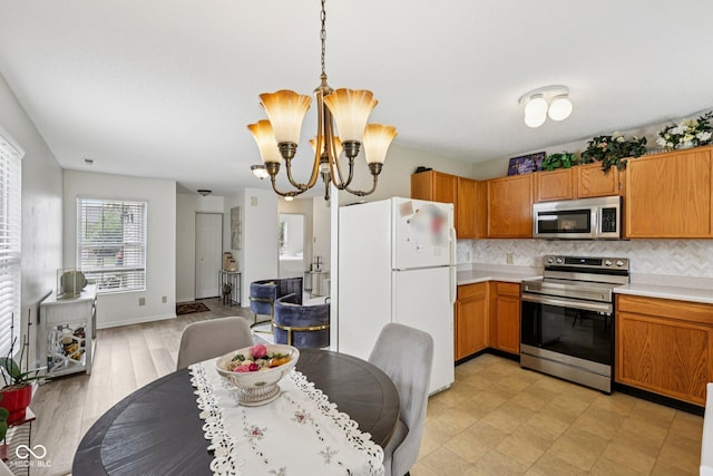 7930 Cork Bend Ln, Indianapolis, IN 46239 - kitchen featuring stainless steel appliances, light countertops, a chandelier, decorative backsplash, and decorative light fixtures