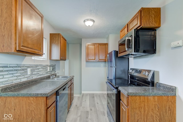 3426 N Olney St, Indianapolis, IN 46218 - kitchen with appliances with stainless steel finishes, light wood-style flooring, dark countertops, decorative backsplash, and a textured ceiling