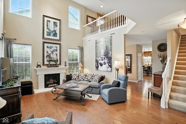 13534 E 131st St, Fishers, IN 46037 - living area featuring stairway, plenty of natural light, wood finished floors, a high ceiling, and a glass covered fireplace