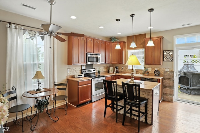 13534 E 131st St, Fishers, IN 46037 - kitchen featuring appliances with stainless steel finishes, a ceiling fan, backsplash, hanging light fixtures, and light wood-type flooring