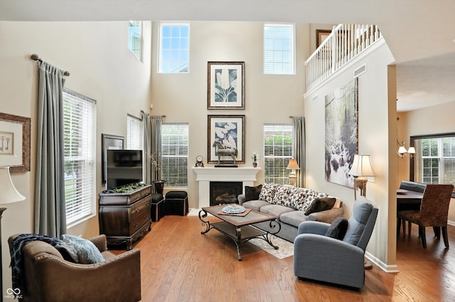 13534 E 131st St, Fishers, IN 46037 - living room with light wood-style flooring, a glass covered fireplace, a high ceiling, and a chandelier