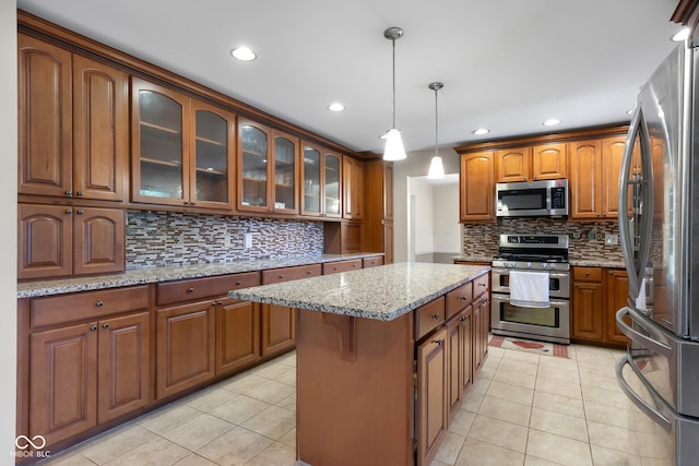 3905 Cove Rd, Columbus, IN 47203 - kitchen featuring appliances with stainless steel finishes, tasteful backsplash, light tile patterned flooring, light stone counters, and brown cabinetry