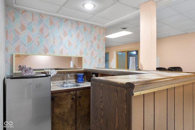 3905 Cove Rd, Columbus, IN 47203 - kitchen with refrigerator, a paneled ceiling, wallpapered walls, and dark brown cabinets