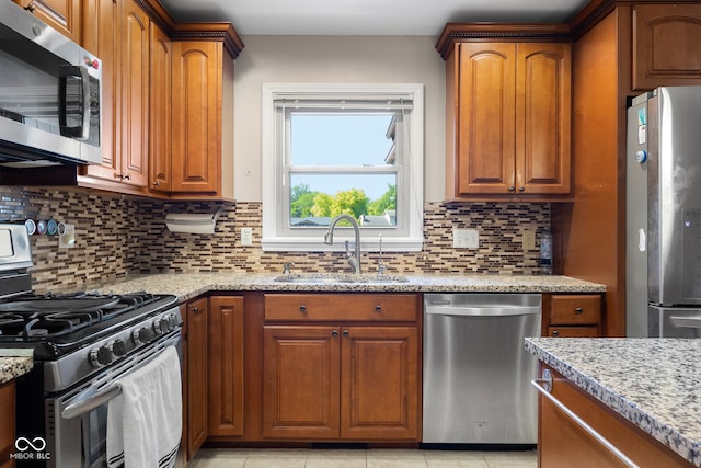 3905 Cove Rd, Columbus, IN 47203 - kitchen featuring stainless steel appliances, light stone countertops, decorative backsplash, and brown cabinets