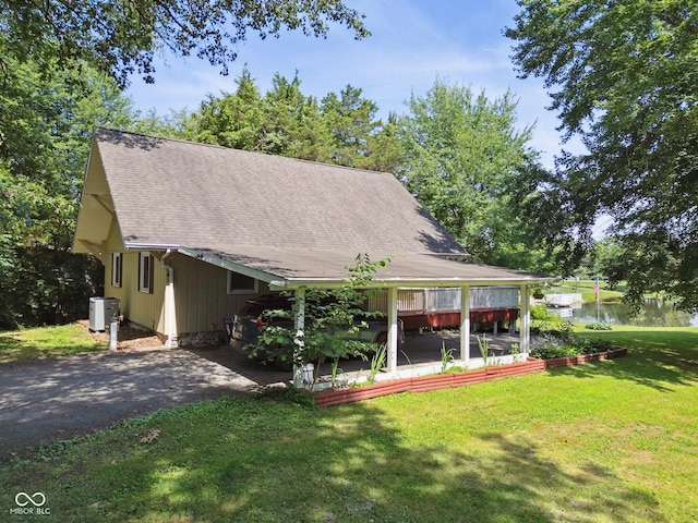 897 Wildwood Rd, North Vernon, IN 47265 - back of house featuring asphalt driveway, a lawn, roof with shingles, a water view, and a carport