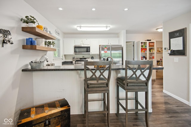 897 Wildwood Rd, North Vernon, IN 47265 - kitchen featuring stainless steel appliances, a peninsula, dark wood finished floors, white cabinetry, and tasteful backsplash