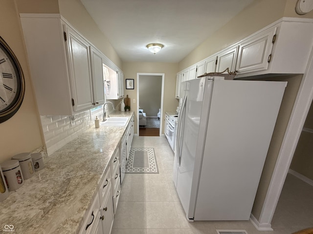 56 E Colony Acres Dr, Brazil, IN 47834 - kitchen with freestanding refrigerator, backsplash, white cabinetry, light tile patterned floors, and light stone countertops