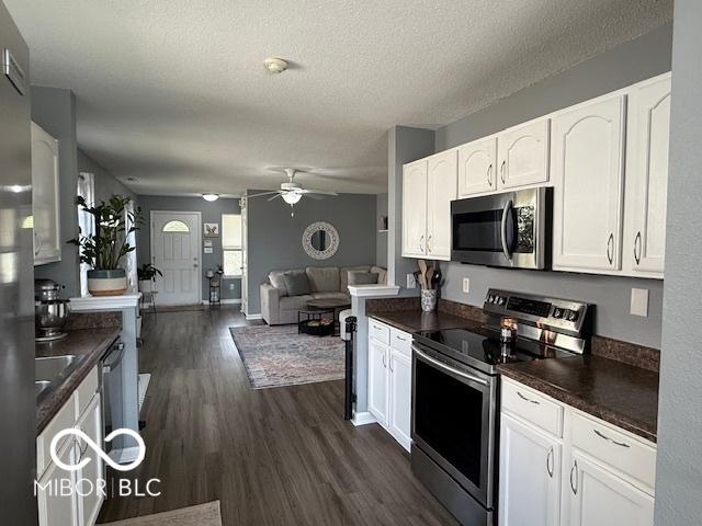 5714 High Timber Ln, Indianapolis, IN 46235 - kitchen featuring stainless steel appliances, dark countertops, open floor plan, white cabinets, and a textured ceiling