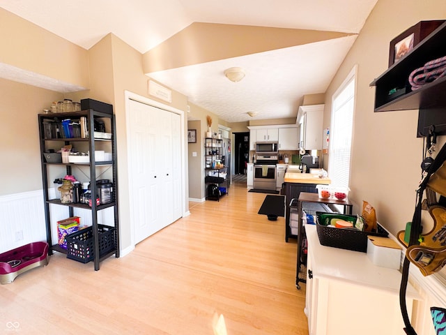 8017 Cardinal Cv W, Indianapolis, IN 46256 - kitchen featuring appliances with stainless steel finishes, light wood-style floors, white cabinetry, light countertops, and vaulted ceiling